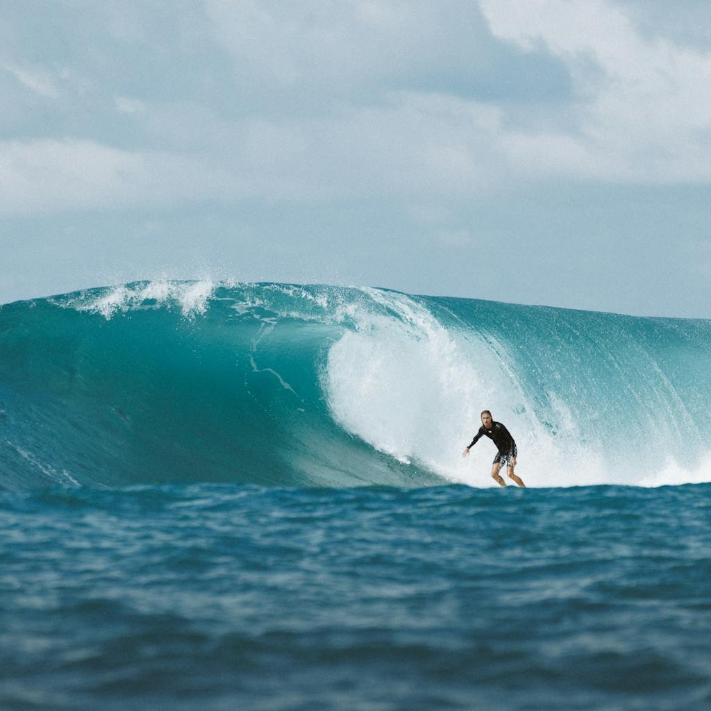 Surfer riding a massive ocean wave in Bali, capturing the thrill and beauty of water sports.